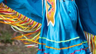 Close-up of the sky blue and multi-coloured fringe on the regalia of a powwow dancer