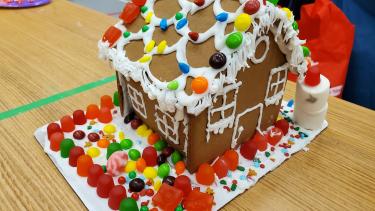 Gingerbread house decorated with gummy candies, skittles and white icing.