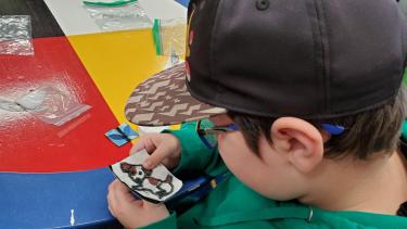A student working on a beading project in the shape of a dog.