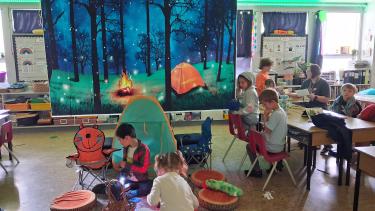 inside a classroom a pretend camp is set up as students move from station to station