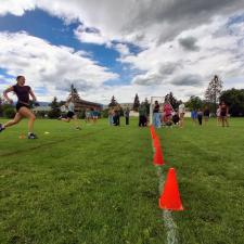 A female athlete sprinting to the finish of a run on a grassy school field